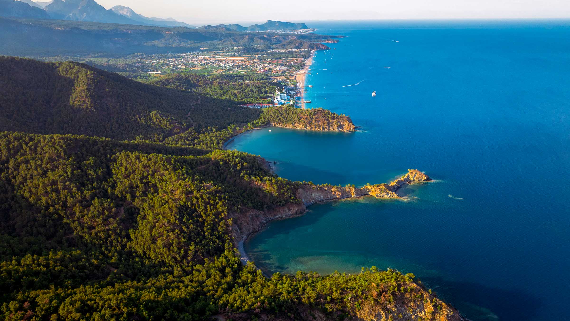 Aerial view of pine-covered headlands and coves on the Kemer coastline