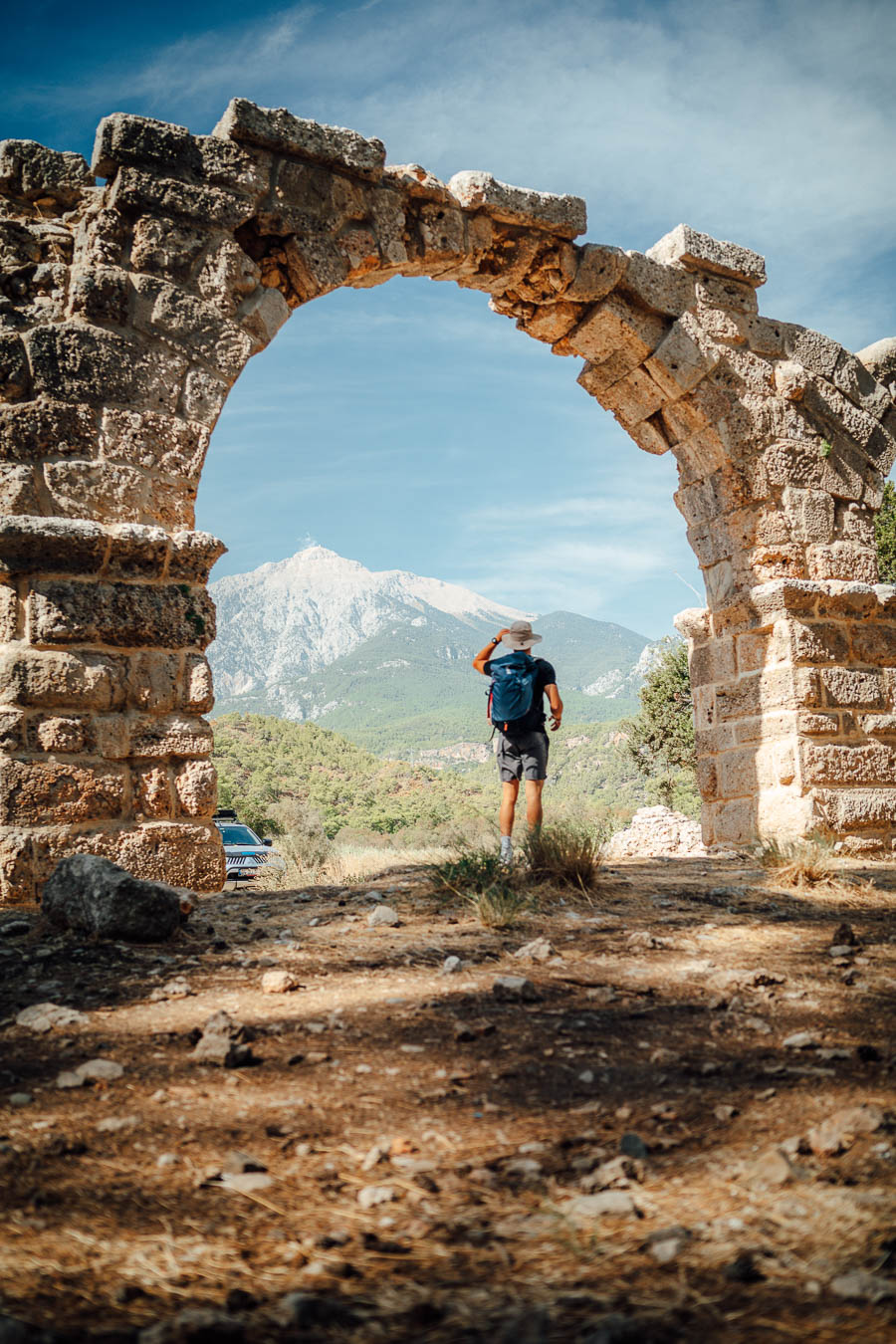 Walker framed by the Roman gate at Phaselis, with Mount Tahtalı behind