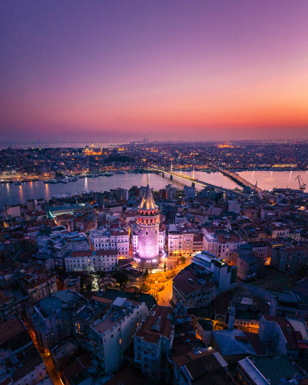 Galata Tower lit up at dusk above the rooftops of Karaköy